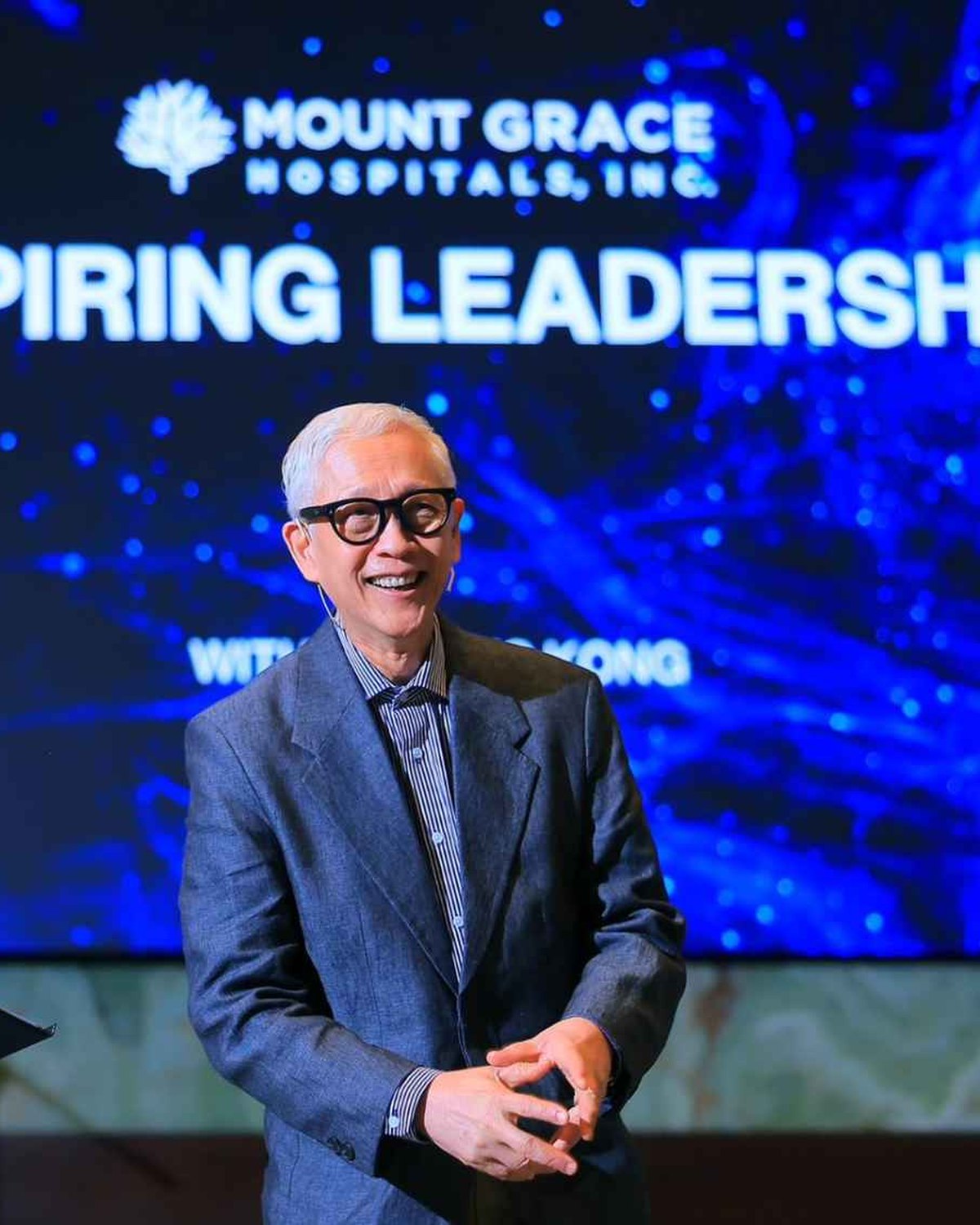 Francis Kong smiling on stage during an Inspiring Leadership session
